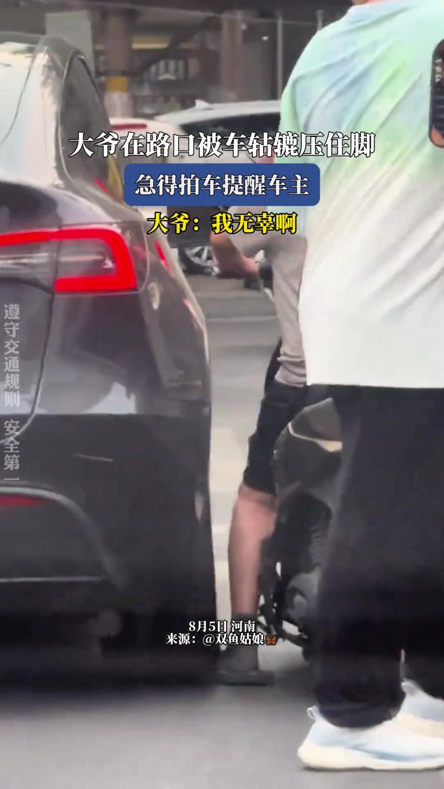 大爷在路口被车轱辘压住脚，急得拍车提醒车主