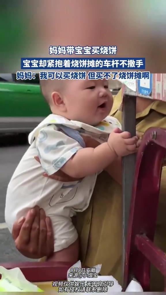 妈妈带宝宝买烧饼，宝宝却紧抱着烧饼摊的车杆不撒手