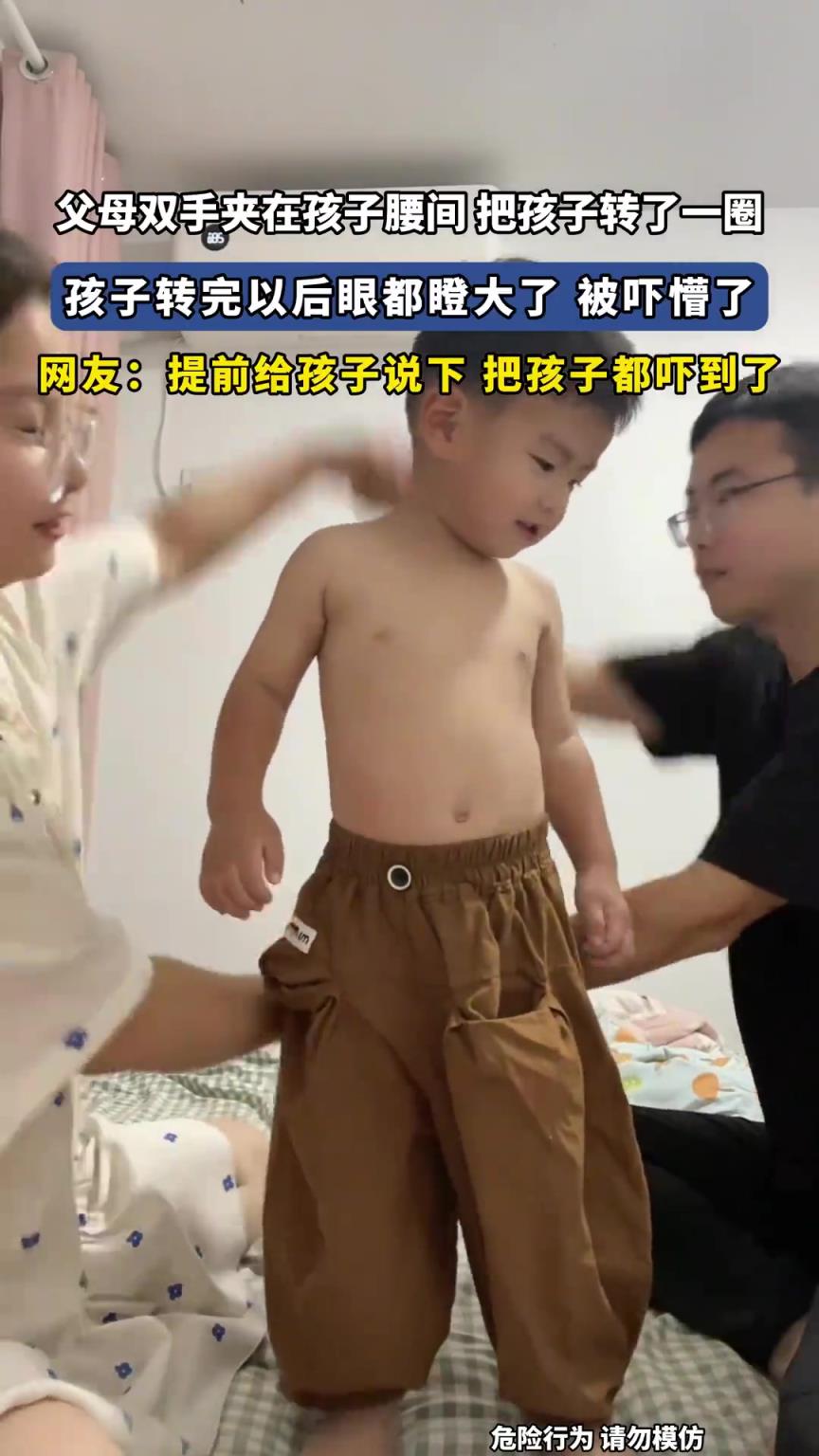父母双手夹在孩子腰间 把孩子转了一圈，孩子转完以后眼都瞪大了