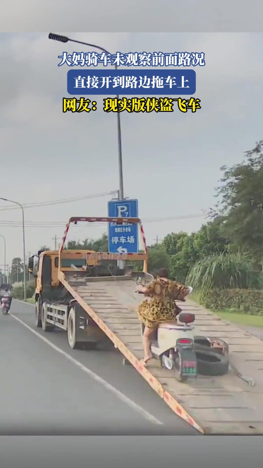 大妈骑车未观察前面路况，直接开到路边拖车上