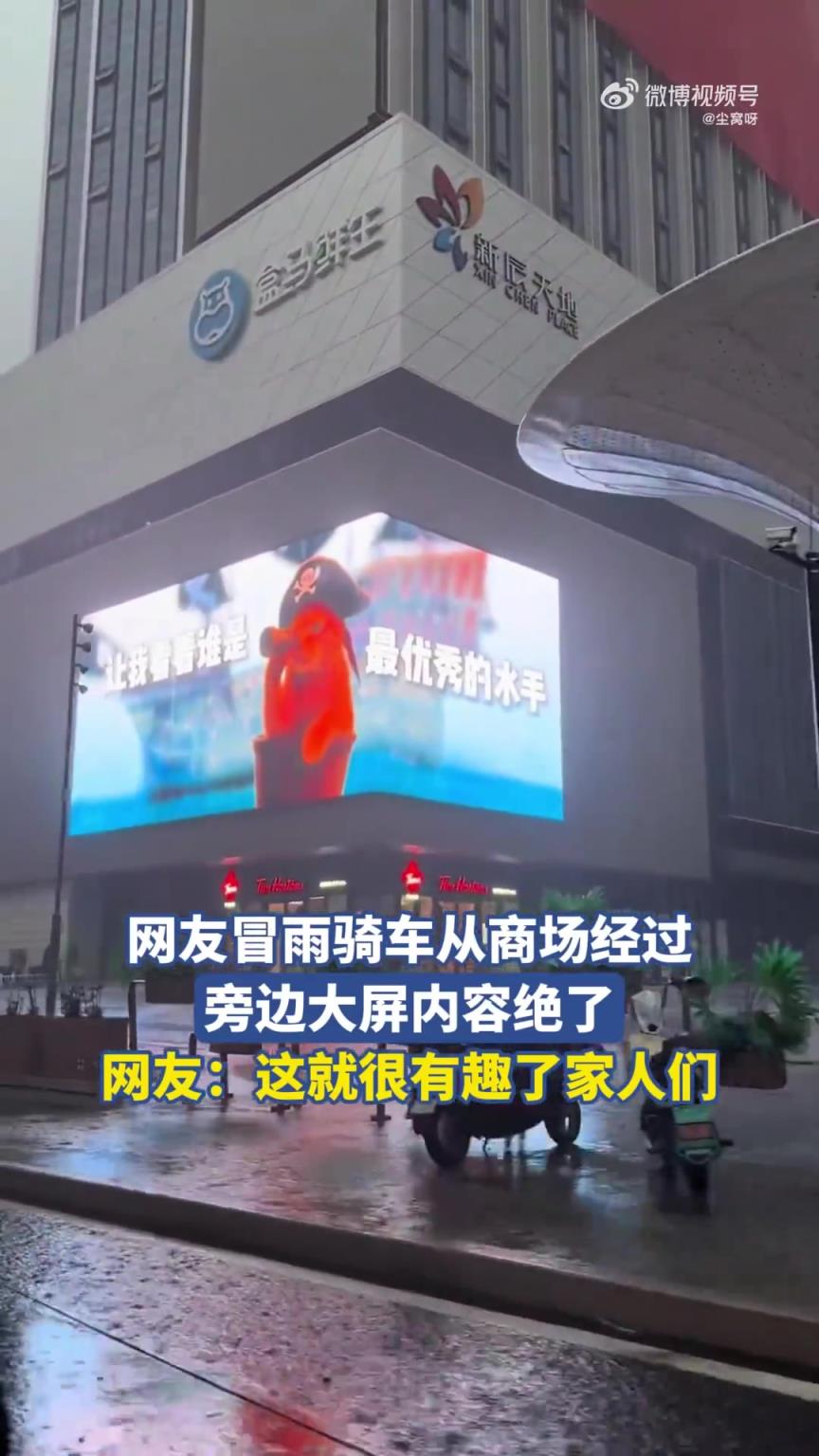 网友冒雨骑车从商场经过，旁边大屏内容绝了