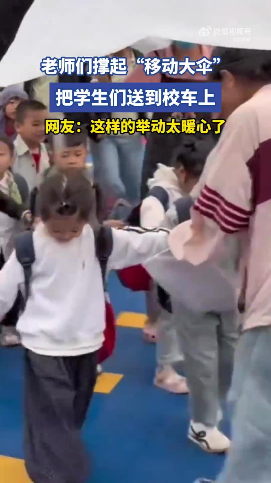 老师们撑起“移动大伞”，把学生们送到校车上