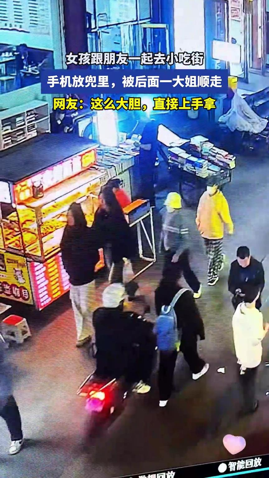 女孩跟朋友一起去小吃街，手机放兜里，被后面一大姐顺走